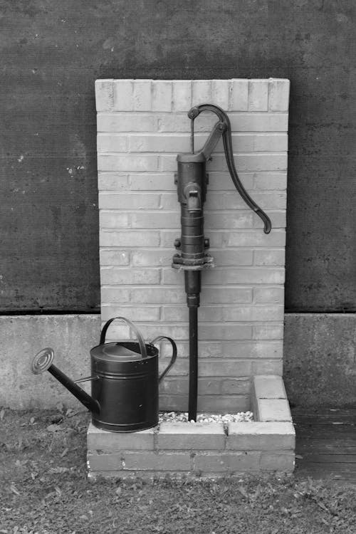 free photo of vintage water pump with watering can black and white